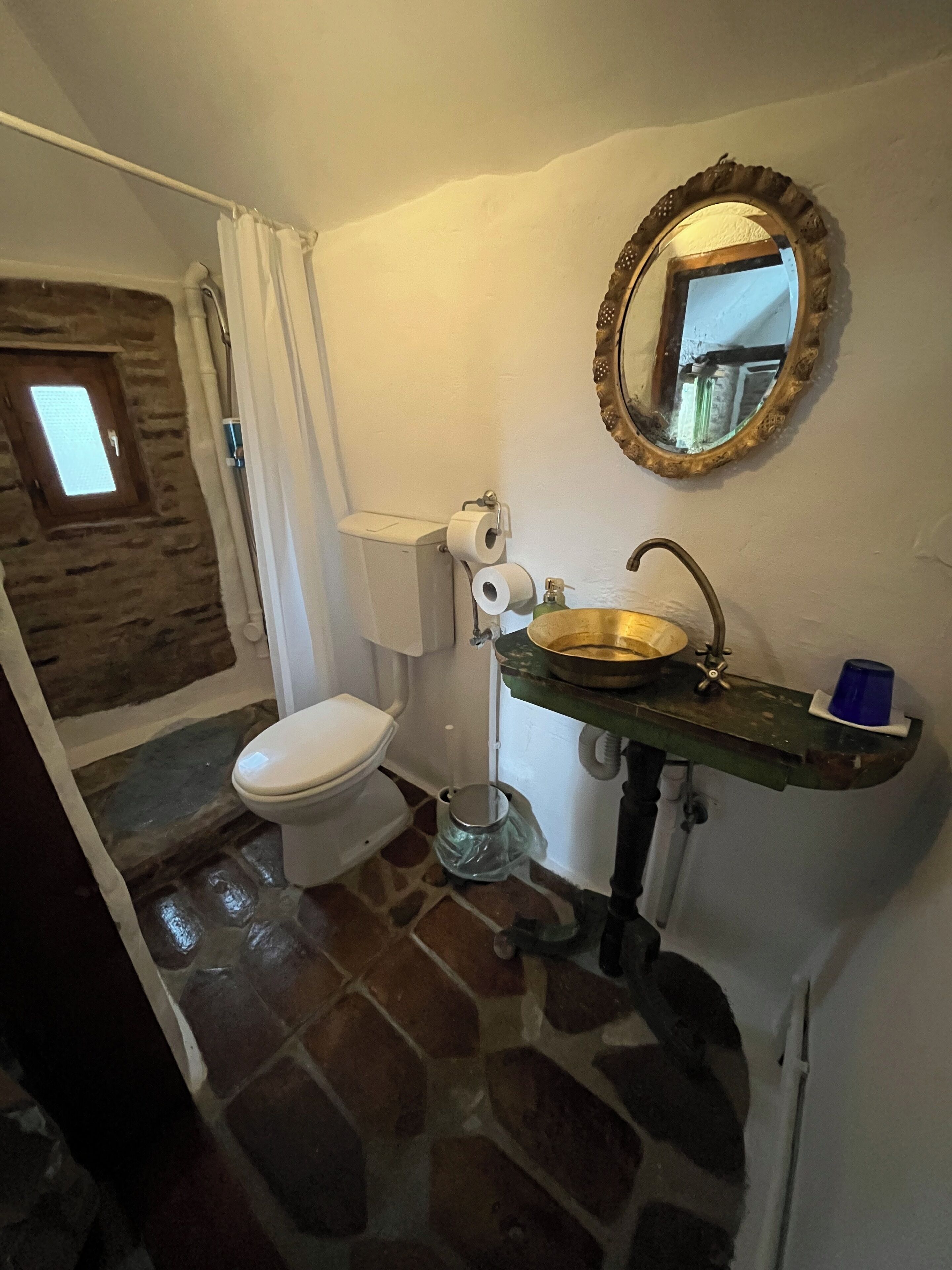 Ein Badezimmer mit Toilette, Waschbecken mit Spiegel und Fenster.