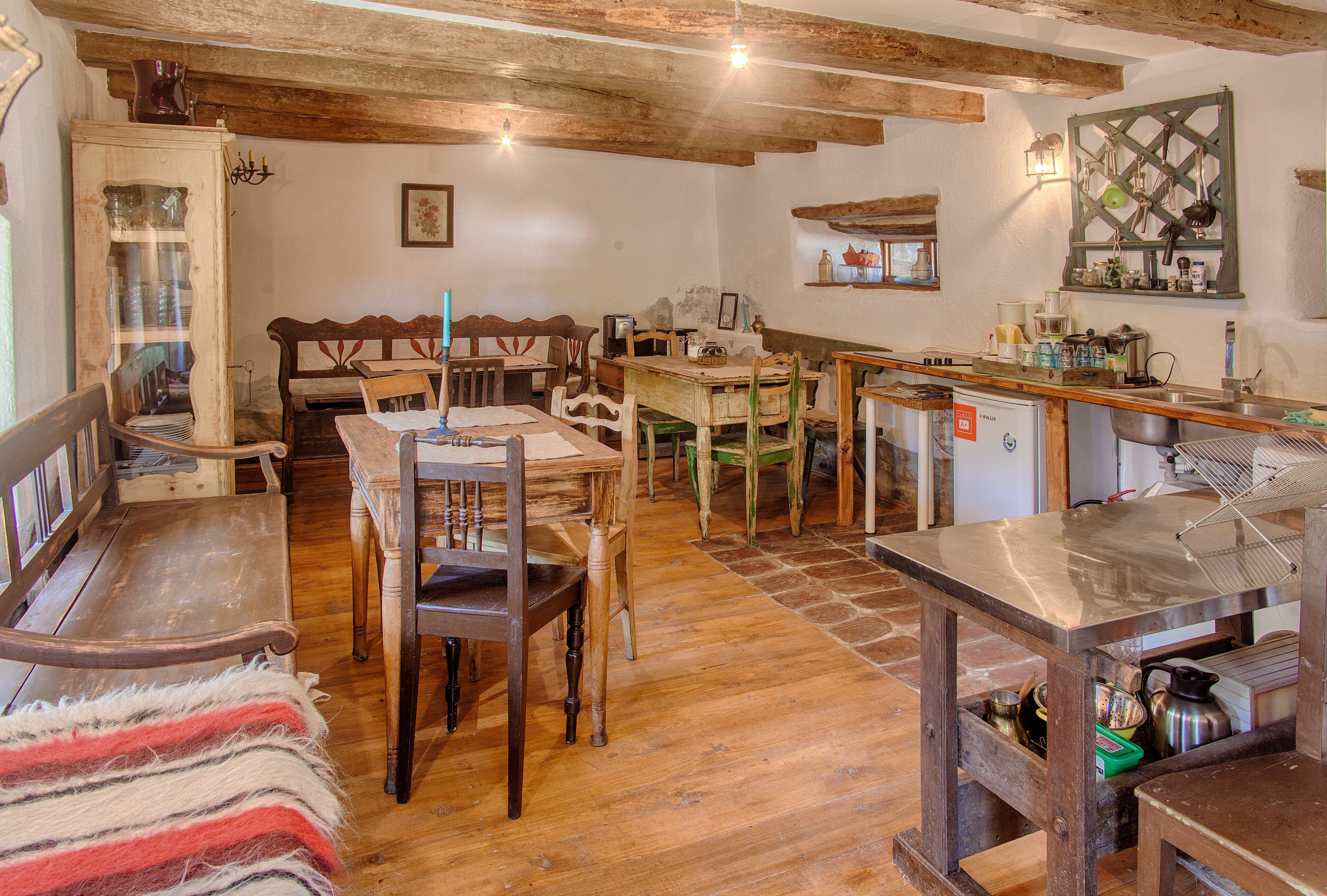 Una cuina rústica amb mobles de fusta, una zona de dinar amb bancs i un petit bar.