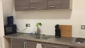 Eine kleine Küche mit Mikrowelle, Spüle und einer Arbeitsfläche.