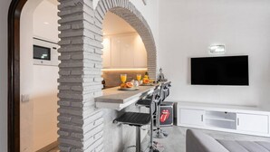Et moderne køkken med en stenhvælv, en bar med barstole, et fladskærms-tv og et Rolling Stones logo på skabet.