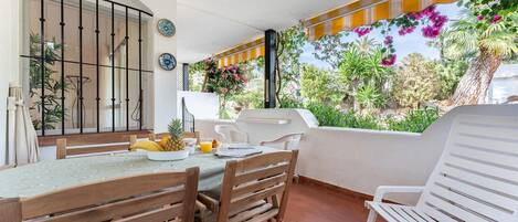 Un patio con tavolo, sedie e barbecue.