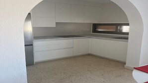 A kitchen with white cabinets, a stainless steel sink, and a window with blinds. - Faro's Retamar Cuddly Nest for 2 (Almería)