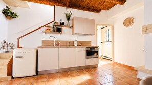 Una cucina con frigorifero bianco, mobili in legno, forno integrato e soffitto in legno.