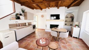 Een moderne keuken met witte kasten, een eethoek met een ronde tafel, en een open haard.