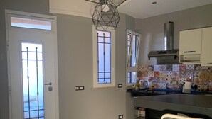 A kitchen with a modern design, featuring a central island, a hanging light fixture, and a tiled backsplash. - Quiet openspace with private access (Roma)