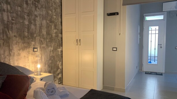 A hotel room with a bed, a wardrobe, a bedside lamp, and a view of the hallway. - Quiet openspace with private access (Roma)