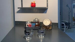 A kitchen counter with a wine rack, a red container, and two shot glasses labeled "CAFFÈ" and "CAFFÈ INVICTA DOPO BUCCINO". - Quiet openspace with private access (Roma)