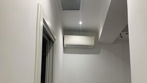 A narrow hallway with white walls, a door on the left, and an air conditioning unit mounted on the wall. - Quiet openspace with private access (Roma)
