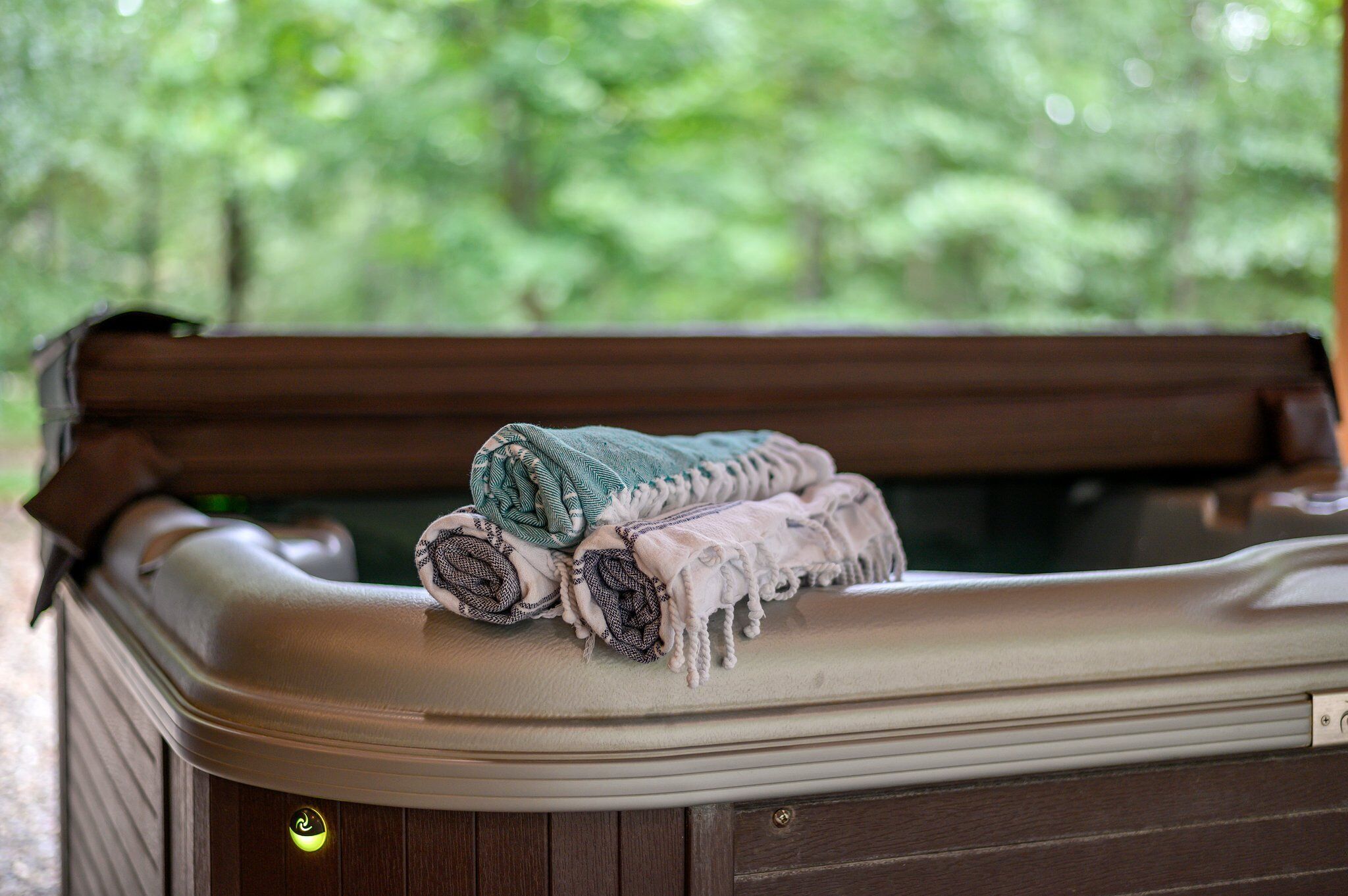 A hot tub with rolled towels and a control panel.