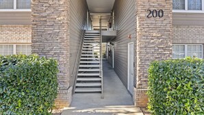 A narrow stairwell leading to an apartment entrance, flanked by stone walls and a hedge. - Fabulous Foley near the beach, ball fields, & OWA (Foley)