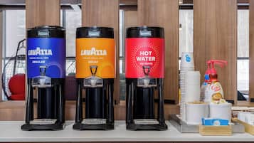 Tres dispensadores de café con la marca 'Lavazza', que ofrecen diferentes opciones: Regular, Descafeinado y Agua Caliente.