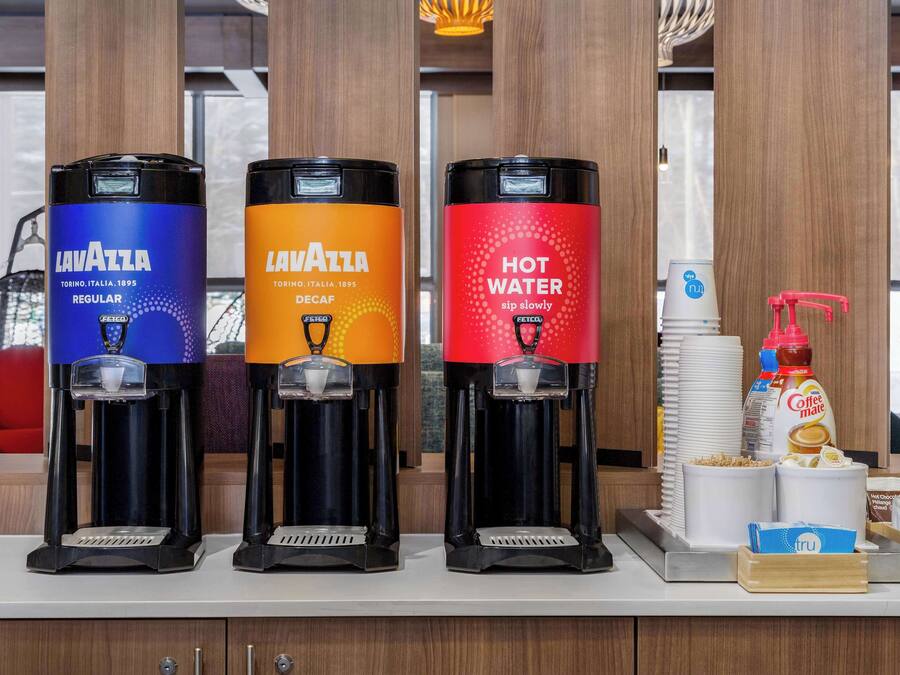 Tres dispensadores de café con la marca 'Lavazza', que ofrecen diferentes opciones: Regular, Descafeinado y Agua Caliente.