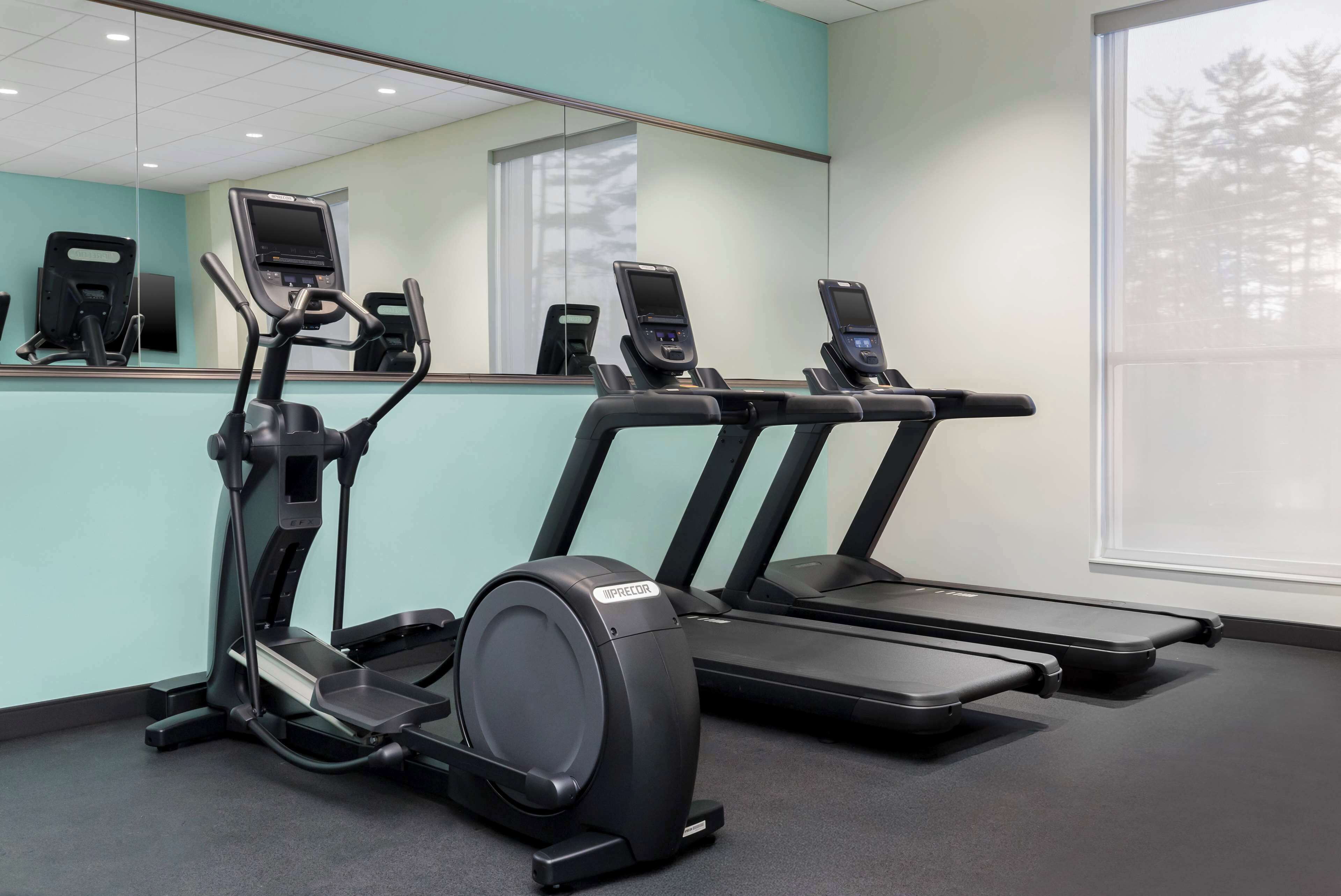 A fitness room with treadmills and an elliptical machine.