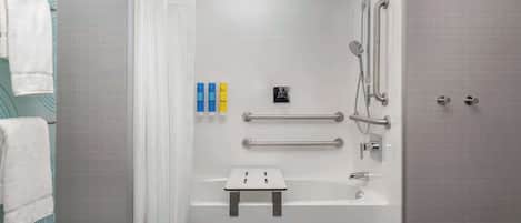 A modern bathroom with a walk-in shower, grab bars, a small stool, and a towel rack.