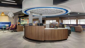 A modern hotel reception area with a circular desk, comfortable seating, and a large window providing natural light. - Tru By Hilton Bracebridge, On (Bracebridge)