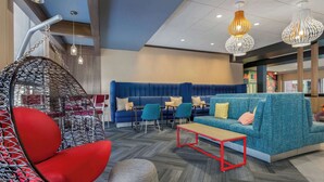 A modern lounge area with a blue sofa, red hanging chair, and a wooden coffee table. - Tru By Hilton Bracebridge, On (Bracebridge)