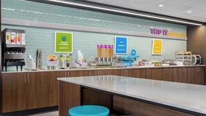 A modern breakfast area with a coffee machine, yogurt and oatmeal dispenser, and a sign advertising pancakes. - Tru By Hilton Bracebridge, On (Bracebridge)