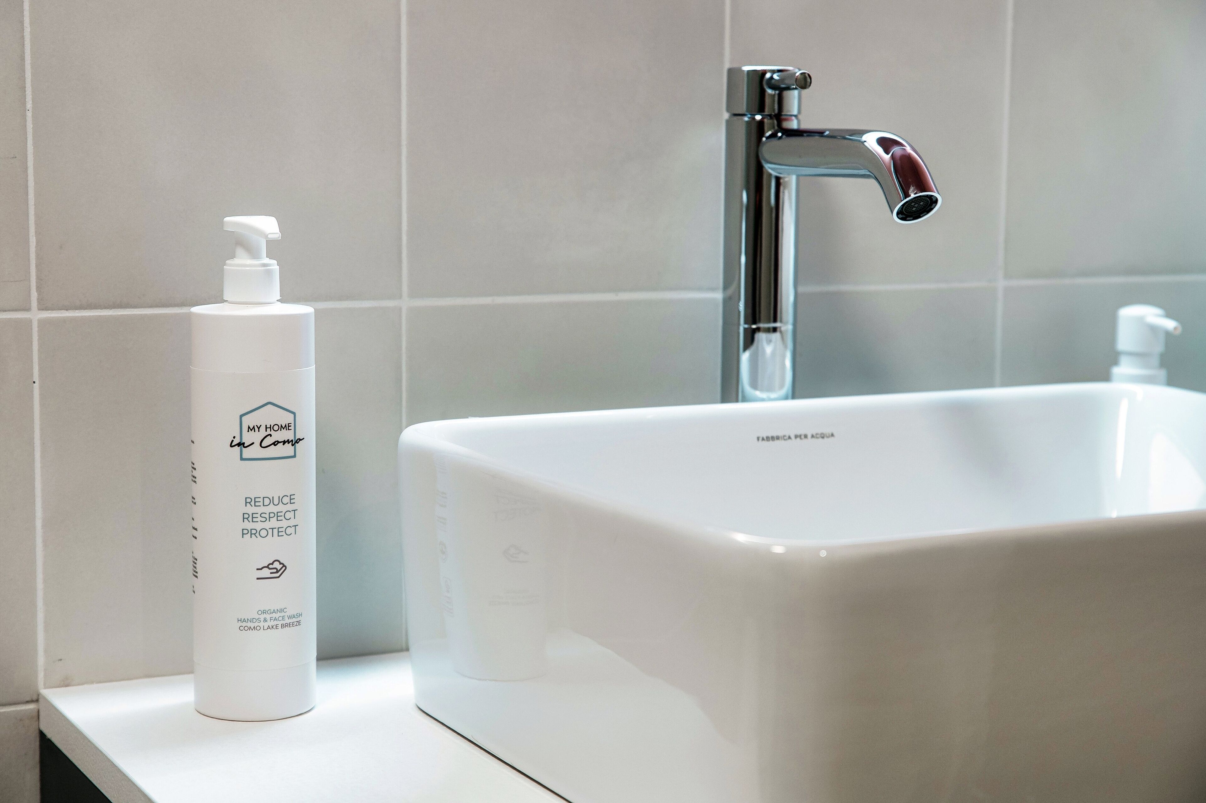 A bathroom with a white sink, a chrome faucet, and a bottle of hand soap.