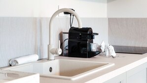 A modern kitchen with a built-in coffee maker, a sink, and a glass of water on the counter. - Marinetti Suite 7 (Como)