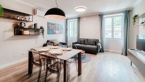 A modern living space with a dining area, a sofa, and a TV. - Marinetti Suite 7 (Como)