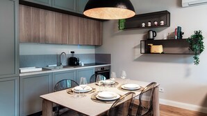 A modern kitchen with grey cabinets, a wooden dining table set with plates and glasses, and a black pendant light. - Marinetti Suite 7 (Como)