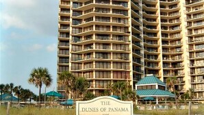 Un hôtel à plusieurs étages, doté de balcons et d’une enseigne indiquant « The Dunes of Panama 7205 ».