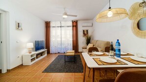 En moderne stue med tv, sofa, spisebord og loftventilator.