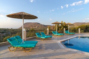 A rooftop pool area with lounge chairs and umbrellas, overlooking a mountainous landscape. - Villa Marietta by Estia (Hersonissos)