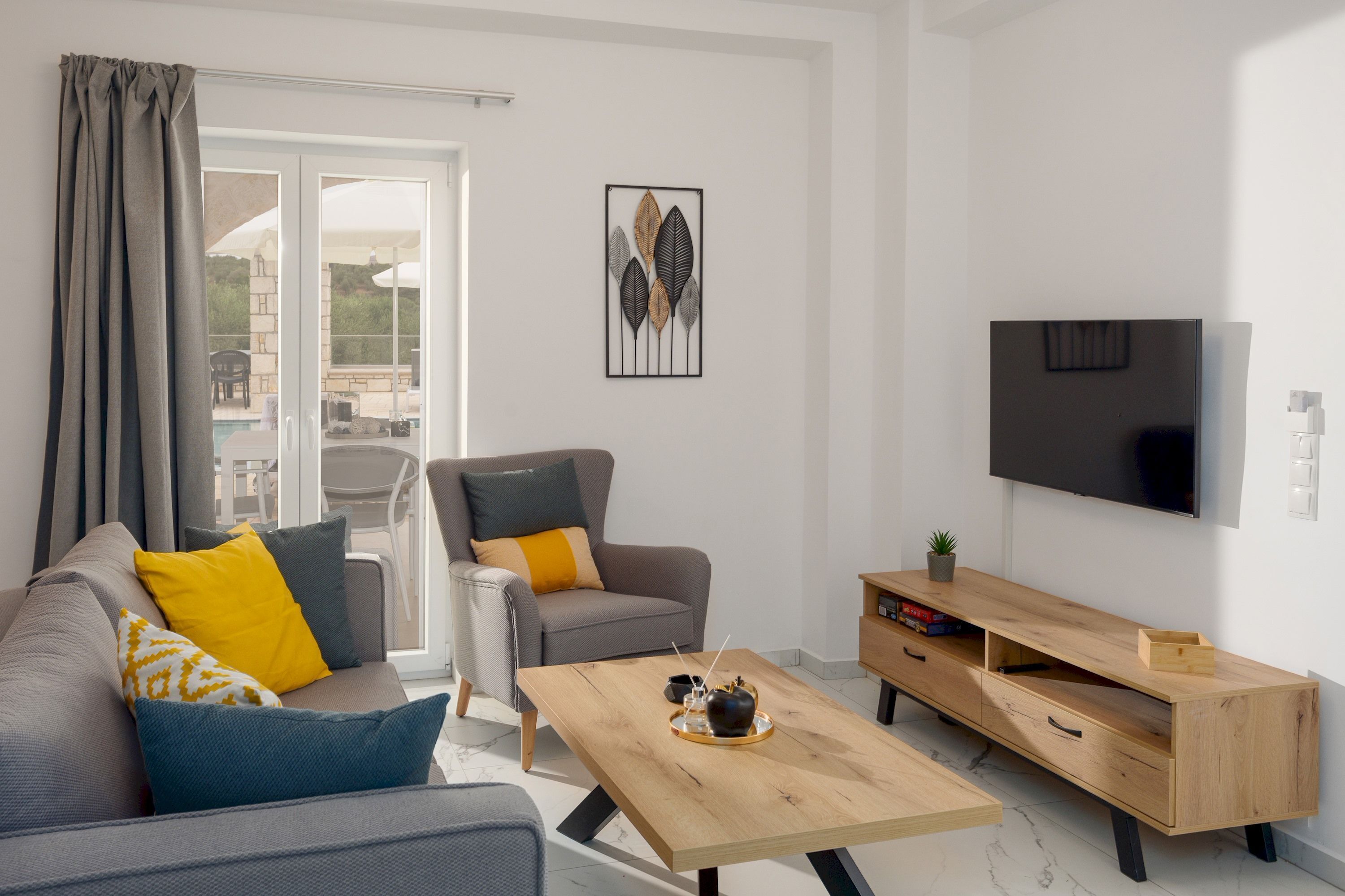 A modern living room with a sofa, armchair, coffee table, TV, and wooden TV stand.