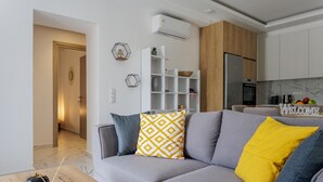 A modern living room with a grey sofa, a wooden cabinet, and a white shelving unit. - Villa Chara by Estia (Mylopotamos)