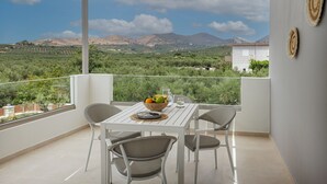 A balcony with a table set for two, overlooking a mountainous landscape. - Villa Chara by Estia (Mylopotamos)