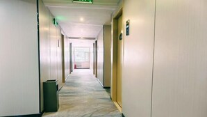 Ein Hotelgang mit Teppichboden, Türen auf beiden Seiten und einem Mülleimer.