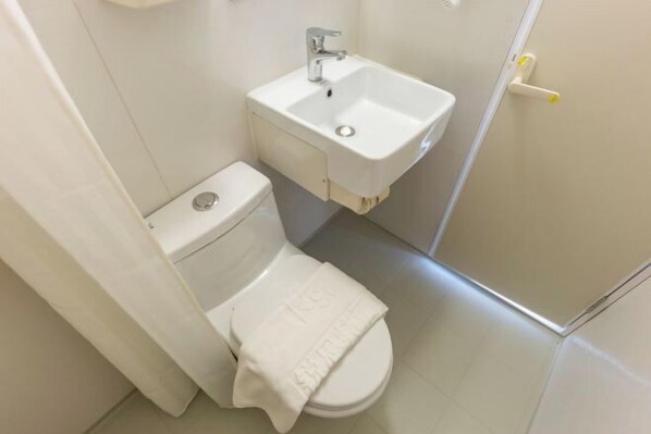 A small, clean bathroom with a toilet, sink, and shower. - Rest Hotel (Lanzhou railway station store) (Lanzhou)