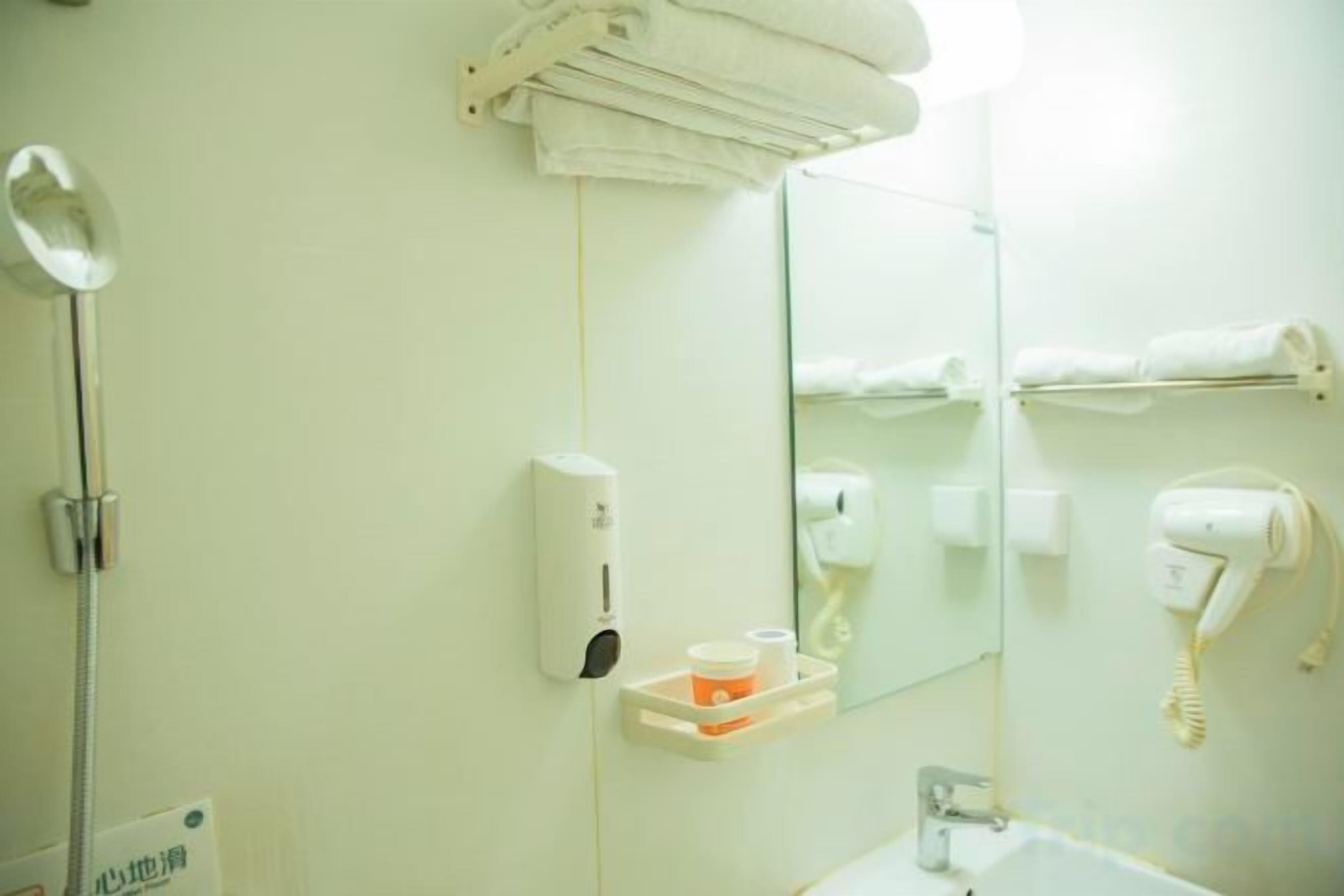 A bathroom with a sink, mirror, towel rack, hairdryer, and a hand dryer.