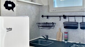 Una cocina moderna con un refrigerador blanco, un lavamanos empotrado y una ventana sobre la encimera.
