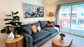 A modern living room with a grey sofa, wooden side tables, a round coffee table, and a ceiling fan.