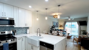 A modern kitchen with white cabinetry, stainless steel appliances, and a central island with a dishwasher.