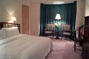 A hotel room with a bed, two chairs, a lamp, and a curtain. - Rosedale Hotel & Suites (Guangzhou)