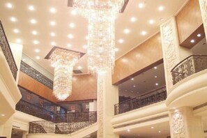 Un atrio de varios niveles con candelabros, barandillas y una imponente escalera.