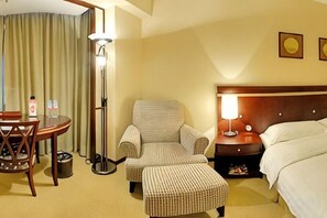 A hotel room with a bed, a chair, a table, and a lamp. - Rosedale Hotel & Suites (Guangzhou)