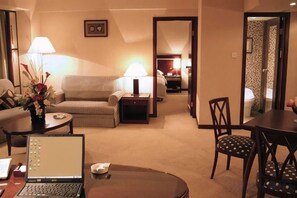 Une chambre d’hôtel avec un canapé, une table à manger, un ordinateur portable et une lampe.