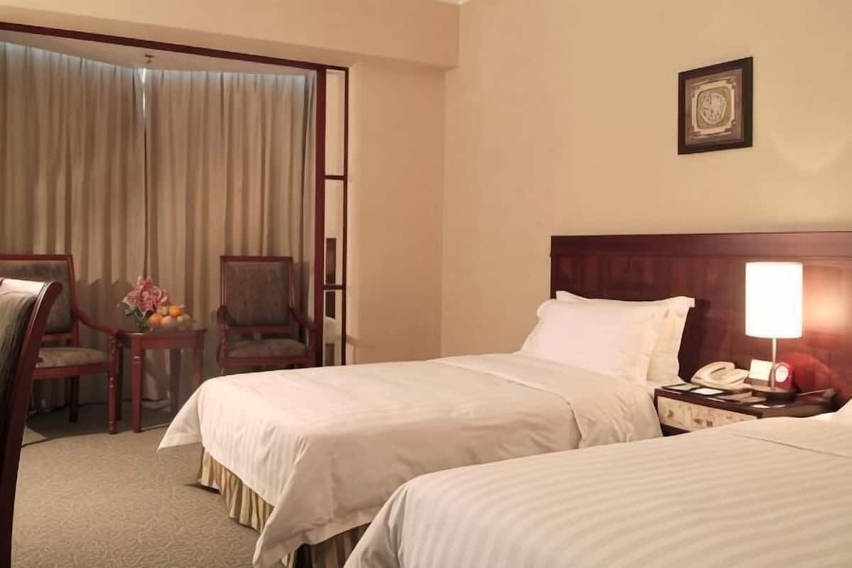 A hotel room with two beds, a desk with a chair, a lamp, and a telephone.