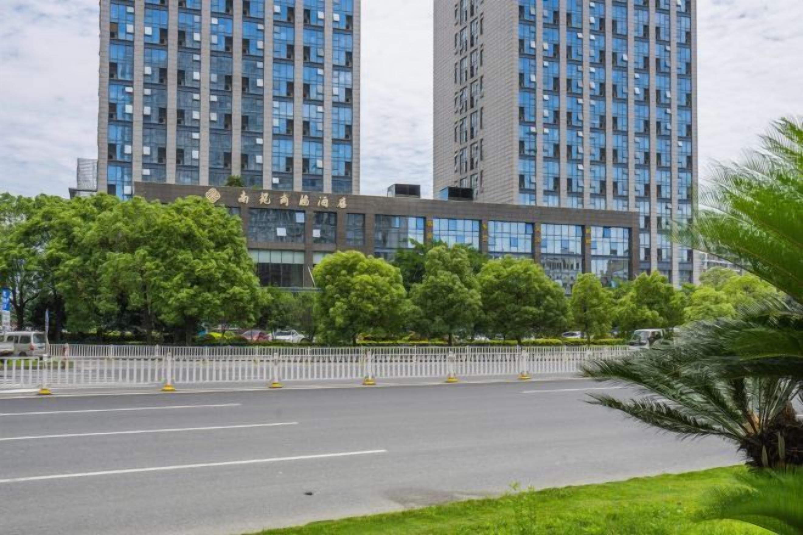 Un edificio moderno con techo plano y ventanas rectangulares, rodeado de vegetación y un cielo despejado.