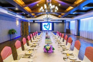 Une salle de conférence avec une longue table préparée pour une réunion, un lustre et un grand écran affichant une forme de cœur.