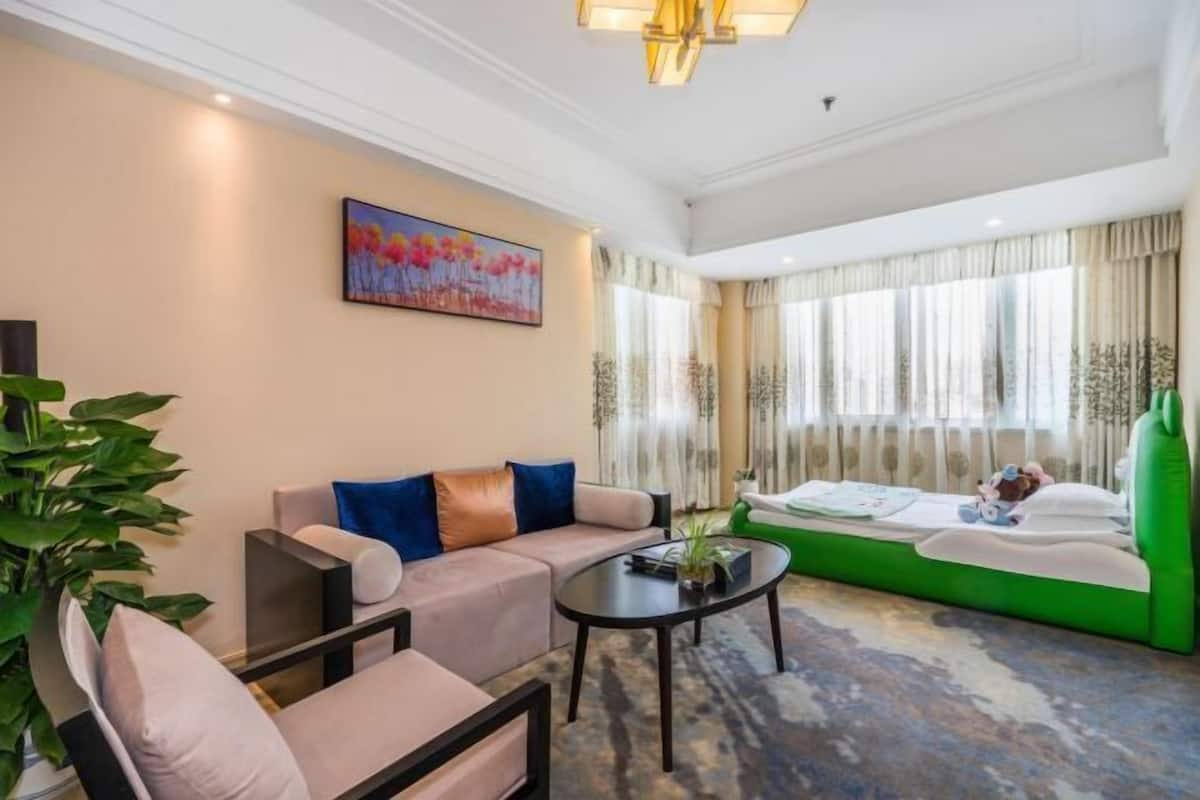 A living room with a sofa, a green couch, a coffee table, and a painting on the wall.