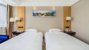 A hotel room with two single beds, a painting on the wall, and two bedside tables with lamps. - Taizhou Sanyou International Hotel (Shili Changjie) (Taizhou)