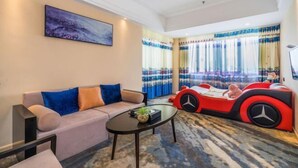 A modern living room with a sofa, a coffee table, and a red car-shaped bed. - Taizhou Sanyou International Hotel (Shili Changjie) (Taizhou)