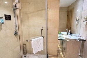 A modern bathroom with a glass shower enclosure, a towel rack, a sink with a mirror, and a toilet. - Taizhou Sanyou International Hotel (Shili Changjie) (Taizhou)