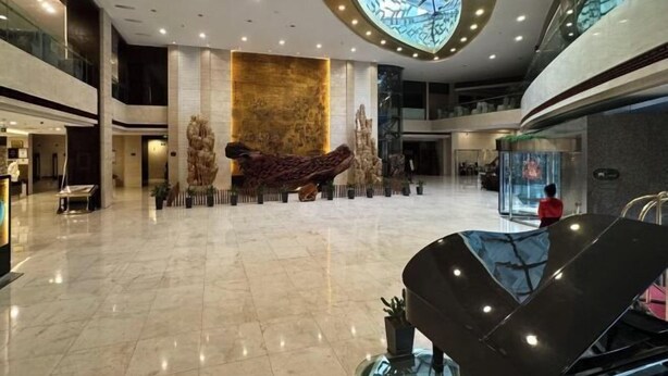 A spacious lobby with a high ceiling, a central sculpture, and a glass elevator. - Taizhou Sanyou International Hotel (Shili Changjie) (Taizhou)