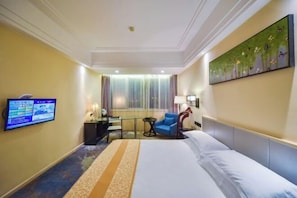 A hotel room with a bed, a desk, a chair, a TV, and a painting on the wall. - Taizhou Sanyou International Hotel (Shili Changjie) (Taizhou)